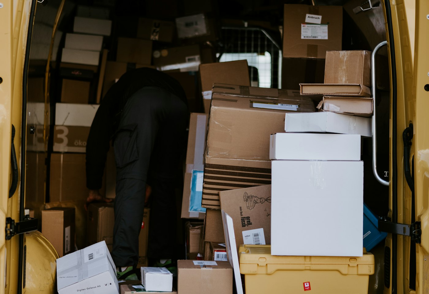 Worker loading cardboard boxes into the back of a delivery van