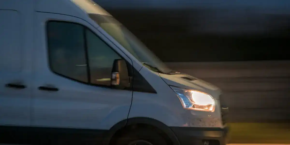 White delivery van driving at dusk